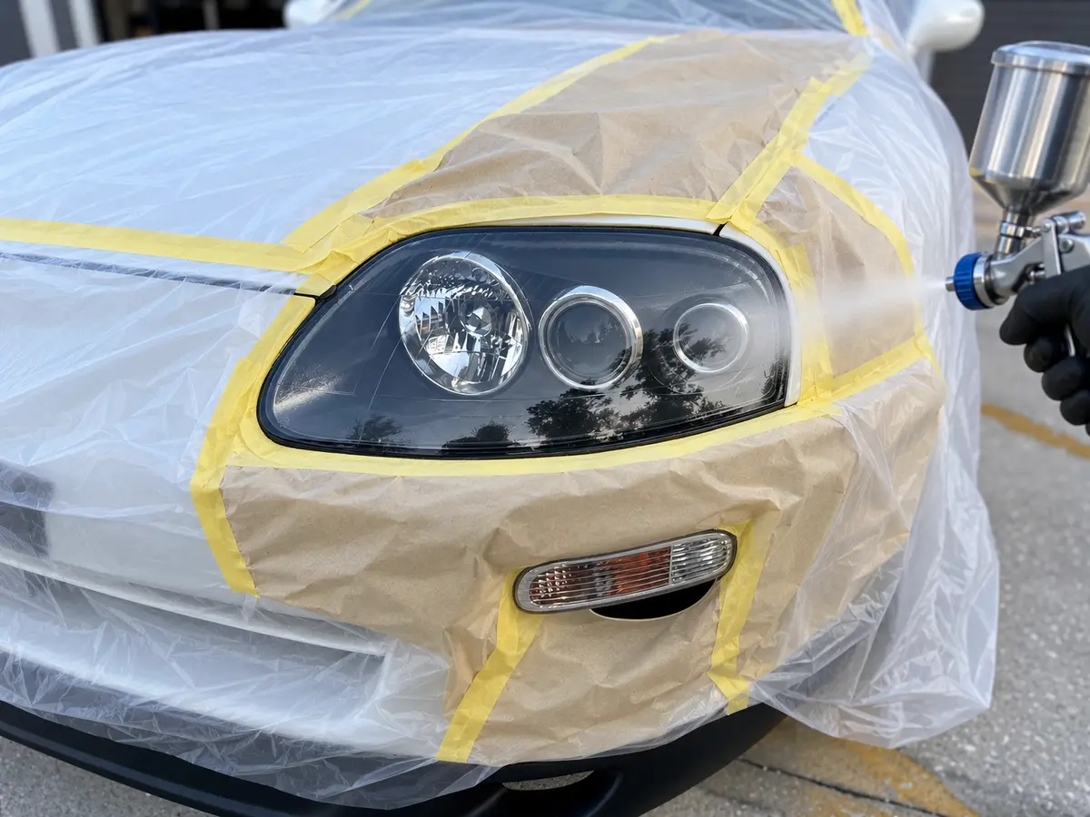 Polycarbonate-specific 2K clear coat being sprayed onto a prepared Toyota Supra headlight